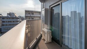 Ein Balkon mit Blick auf die Stadtlandschaft, eine Schiebeglastür und eine eingebaute Klimaanlage.