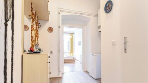 Ein Korridor mit Holzboden, einer zurückliegenden Tür, die in ein Schlafzimmer führt, und einer weißen Wand mit einer Zierplatte.