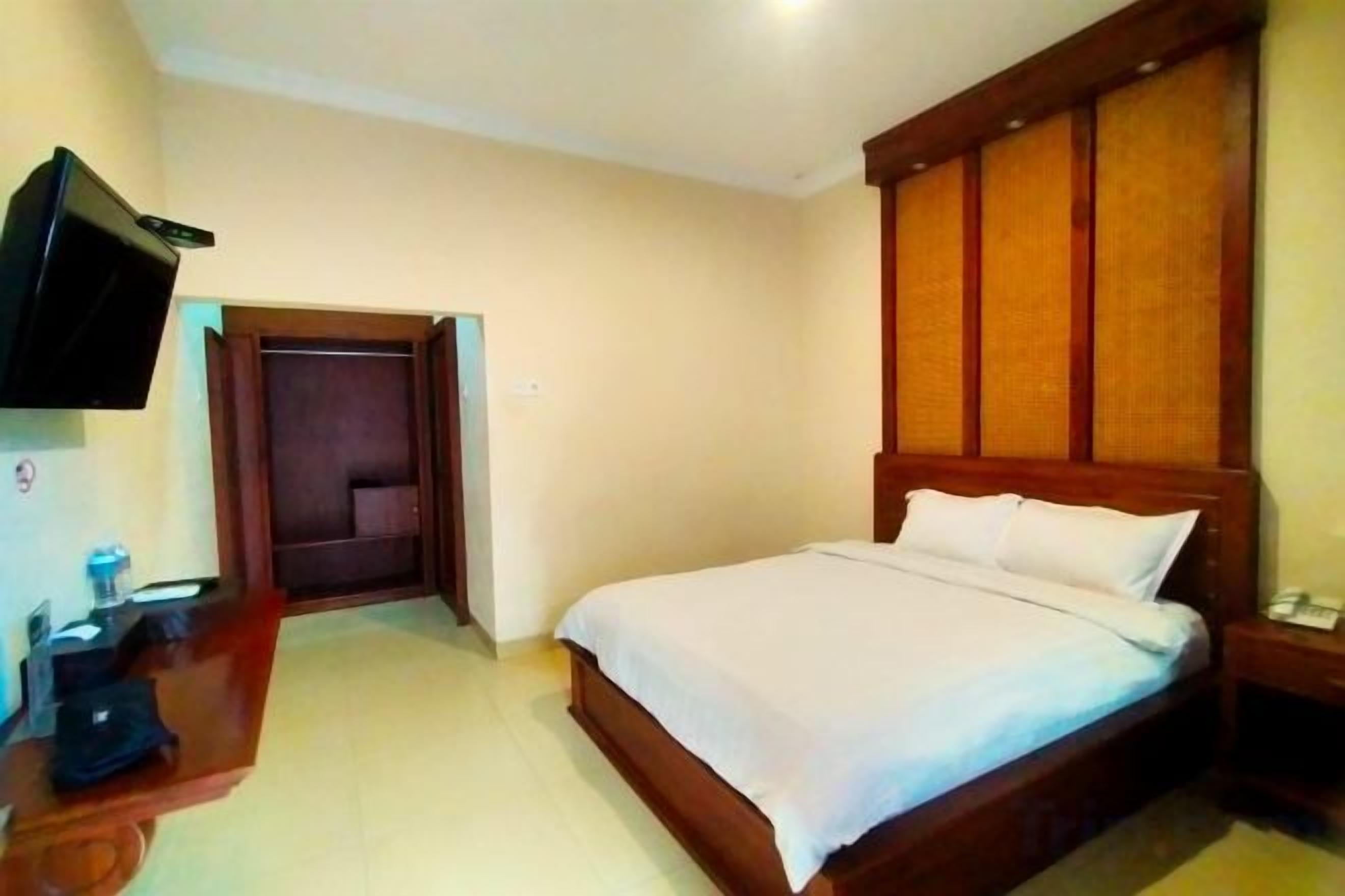 A hotel room with a bed, a television, a desk, and a wardrobe.