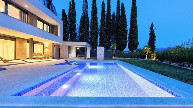 Una casa moderna con piscina, ventanas amplias y un césped cuidado.