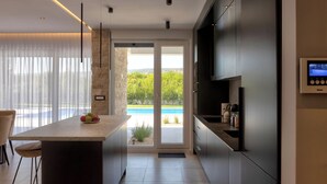 Una cocina moderna con una isla grande, horno empotrado y vista a una piscina.