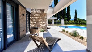 Un patio exterior moderno con piscina, muro de piedra y zona de estar.