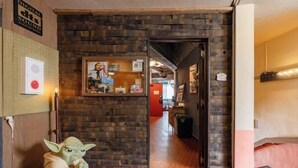 Un couloir avec un mur en briques, un tableau encadré et une figurine de Yoda.