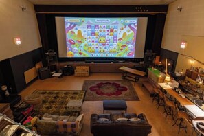 A cozy living room with a large screen, comfortable seating, and a bar area. - Noctarium - MountCinema (Gotemba)