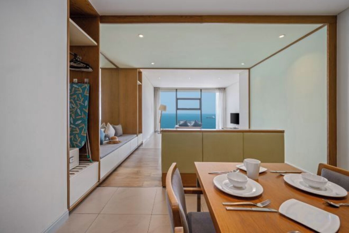 Habitación de hotel moderna con comedor, vista al mar y kitchenette.