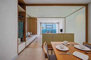 A modern hotel room with a dining area, a view of the sea, and a kitchenette. - The Salt Collections Apartment Sea View Da Nang (Da Nang)