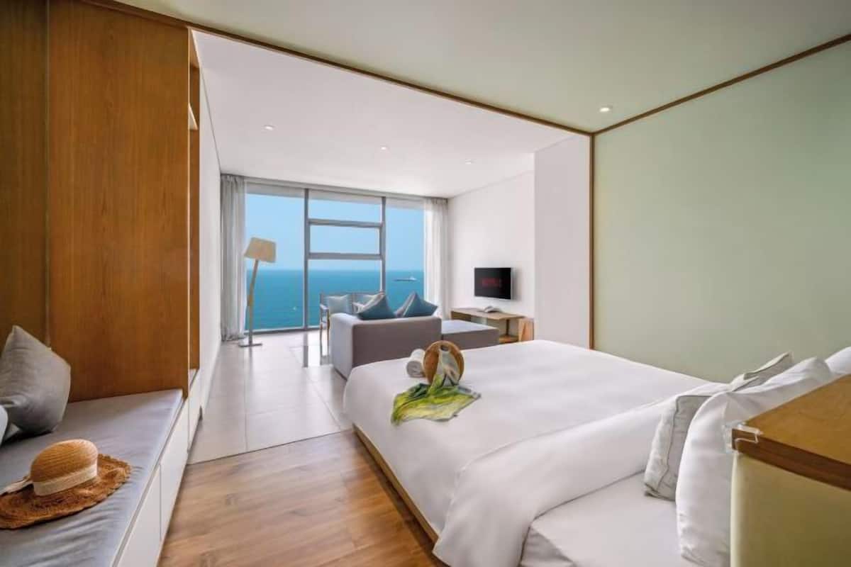 A modern hotel room with a large bed, a seating area with a view, and a television.