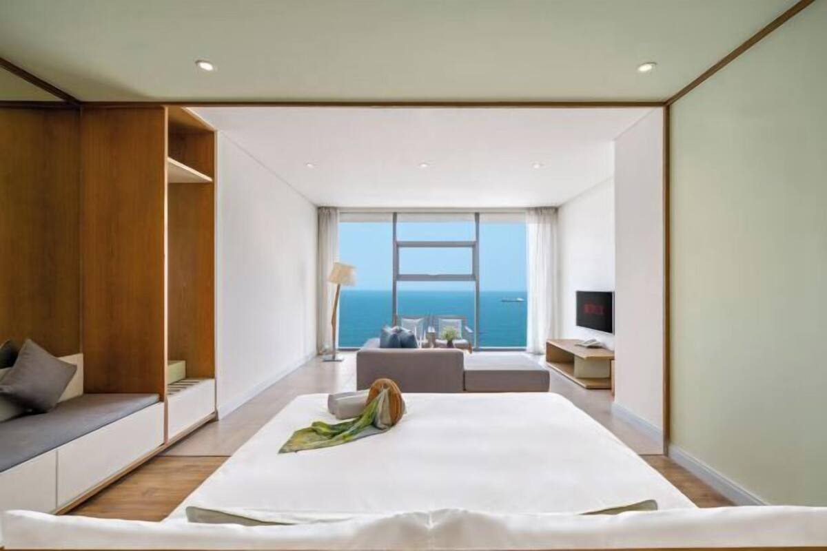 Une chambre d’hôtel moderne dotée d’un grand lit, d’un coin salon et offrant une vue sur la mer.