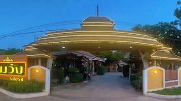 A hotel entrance with a traditional architectural style, a covered walkway, and a signboard.