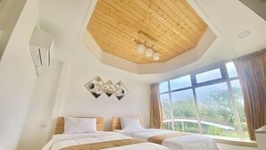 Une chambre avec deux lits, un plafond en bois et une grande fenêtre donnant sur un paysage verdoyant.