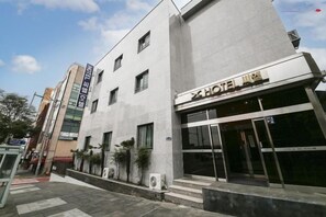 Un hotel con fachada moderna, amplias ventanas y una entrada visible.