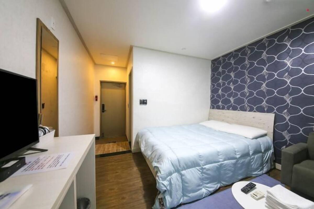 A hotel room with a bed, a TV, a desk, and a chair.