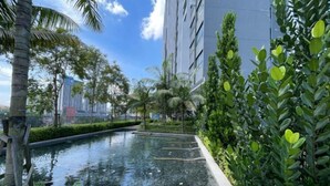 A serene indoor pool area with a tiled floor, surrounded by lush greenery and tall buildings in the background. - The Pano at Jalan Ipoh Near KLCC By The Homez (Kuala Lumpur)