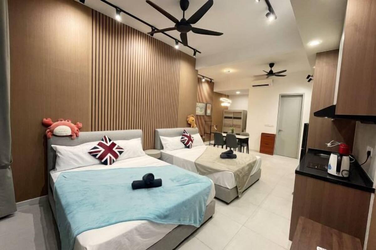 Ein Hotelzimmer mit zwei Betten, einer Küchenzeile, einem Deckenventilator und einer kleinen Essecke.