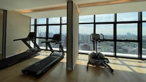 A gym with treadmills and an elliptical machine, large windows with a city view. - The Pano at Jalan Ipoh Near KLCC By The Homez (Kuala Lumpur)