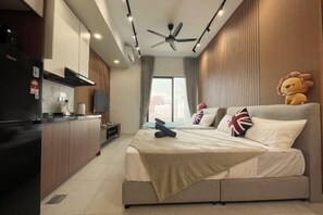 Ein modernes Hotelzimmer mit Bett, kleinem Schreibtisch, Deckenventilator und großem Fenster.