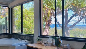 A bathroom with a bathtub, a vanity with a mirror, and a window with a view of trees and mountains. - Casa Vista- House With A View. A Unique Spanish Style Home (Ilkley)