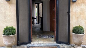 A stone-paved entrance with two potted plants, a rug, and a door leading to an interior space. - Casa Vista- House With A View. A Unique Spanish Style Home (Ilkley)