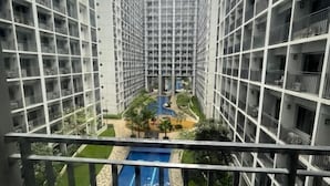 A high-rise residential building with a central courtyard featuring a swimming pool, surrounded by greenery and a small bridge. - Coast Apartment (Pasay)