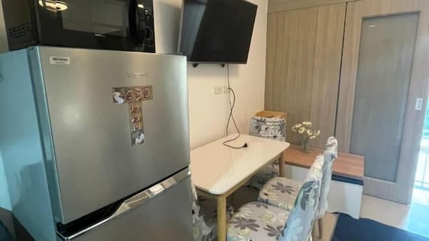 A compact kitchen with a refrigerator, microwave, and flat-screen TV. - Coast Apartment (Pasay)