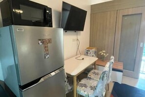 A compact kitchen with a refrigerator, microwave, and flat-screen TV. - Coast Apartment (Pasay)