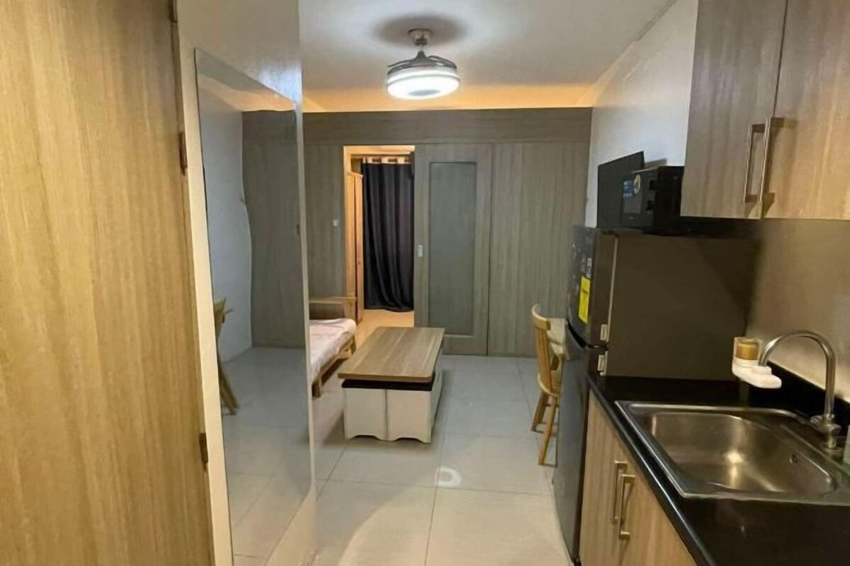 A compact kitchen with a sink, a microwave, and a small dining area with a table and chairs.