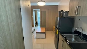 A compact kitchen with a refrigerator, microwave, and sink. - Coast Apartment (Pasay)