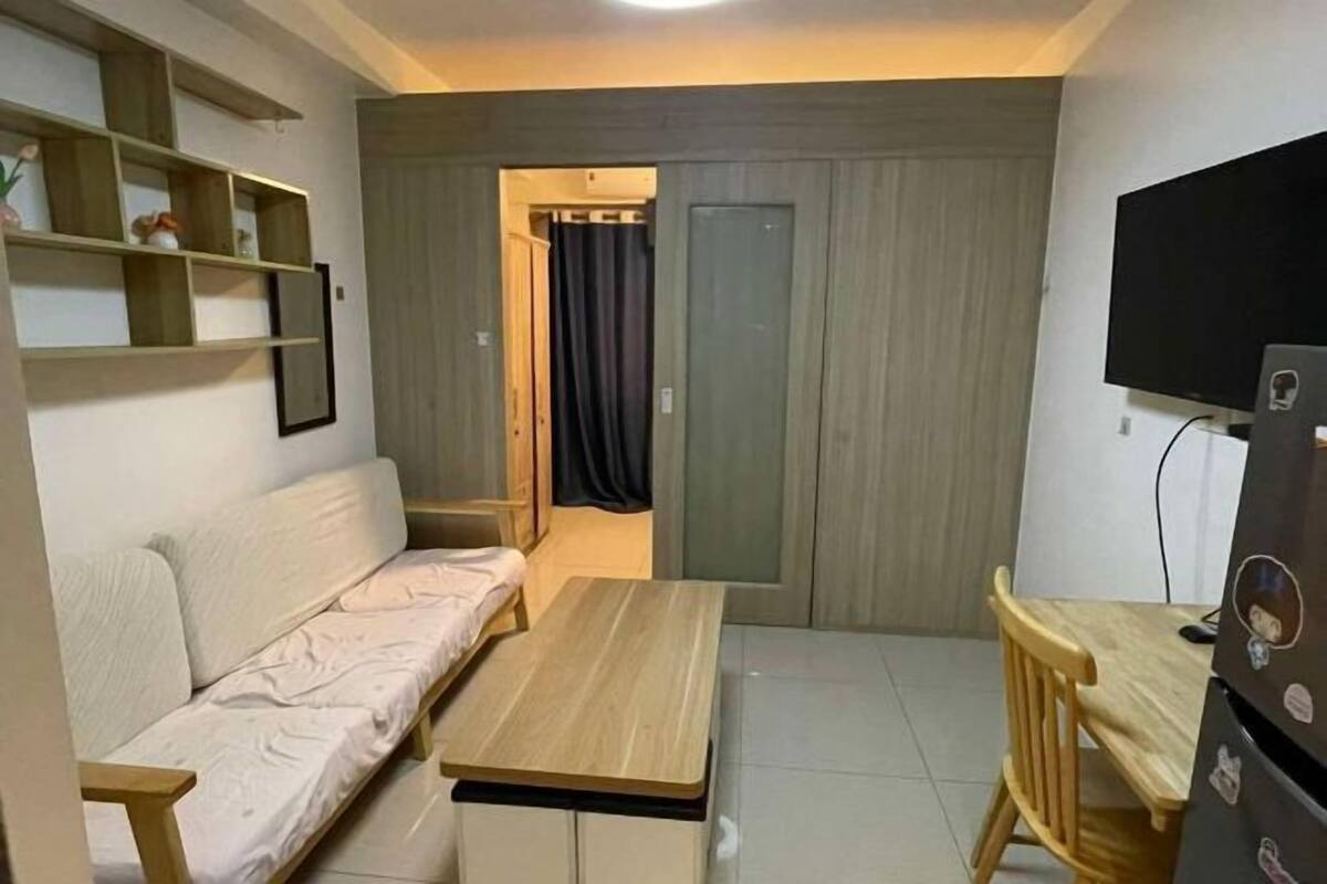 Un espace de vie compact comprenant un canapé, une petite table, un téléviseur et une armoire.