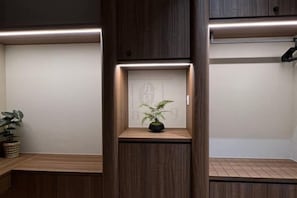 A hotel room with a wooden bench, a small shelf with a plant, and a wall with a decorative panel. - Urban Suites Jelutong 3BR Apartment with Infinity Pool · Near George Town · 18min to Airport (George Town)