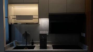 A kitchen with a sink, a faucet, a soap dispenser, and a towel hanging on a rack.