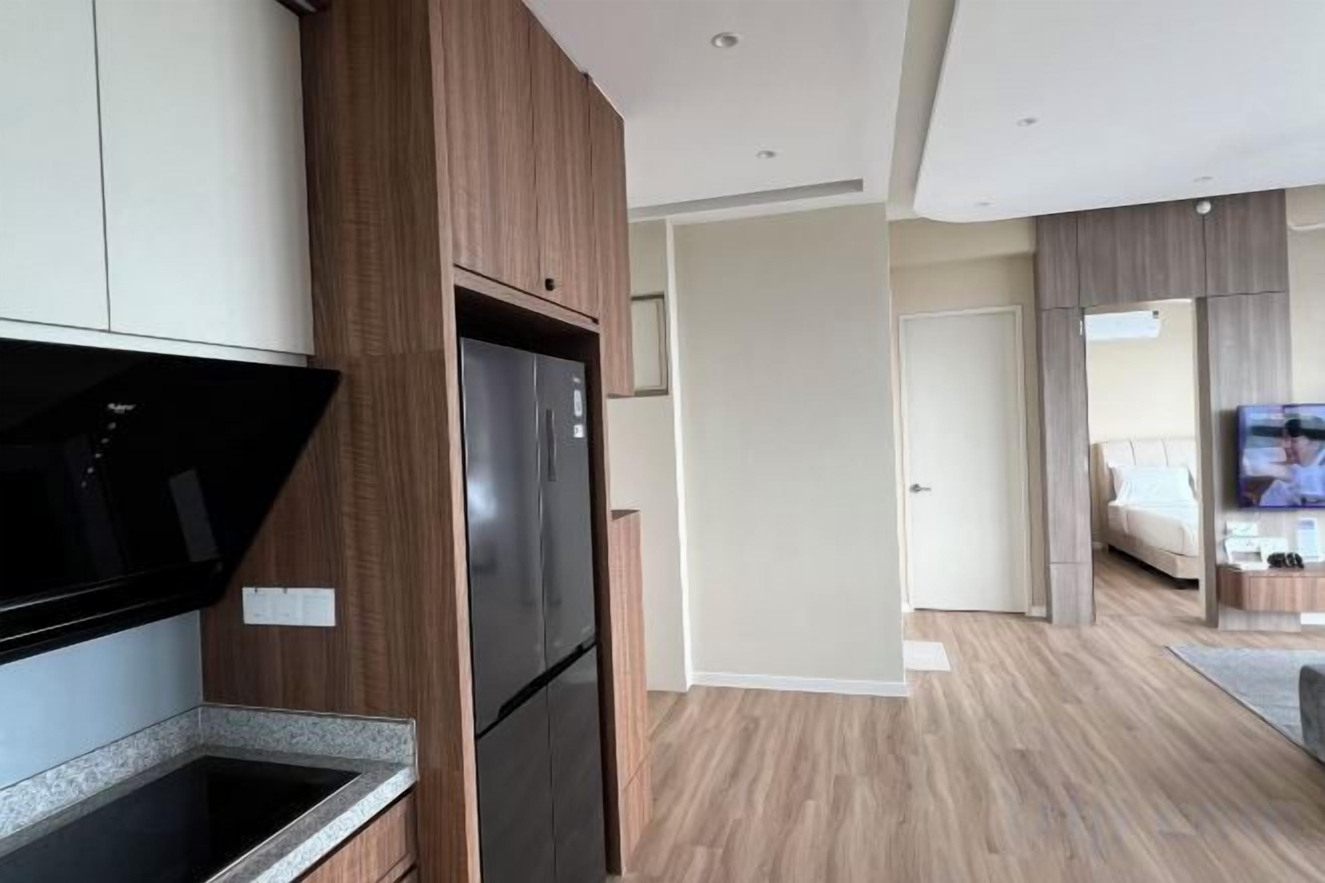 A modern kitchen with a built-in microwave, a black refrigerator, and wooden cabinets.