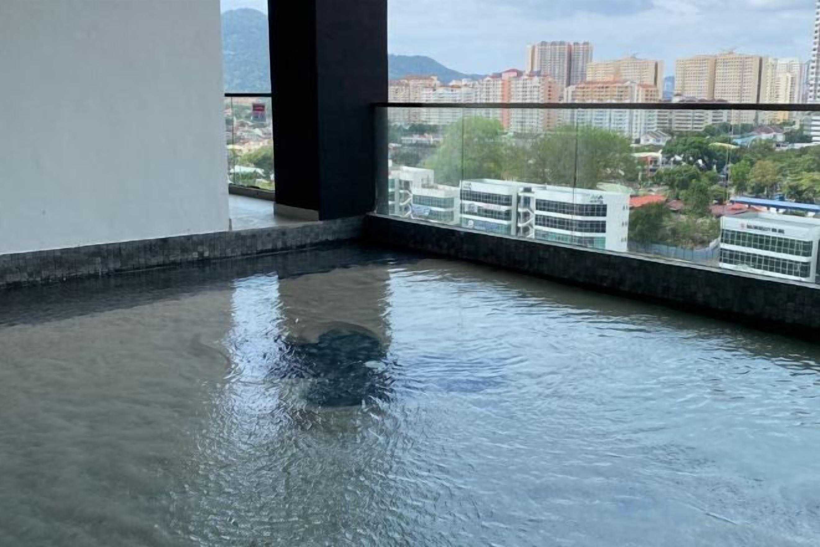A room with a large window overlooking a cityscape, a water feature, and a view of buildings.