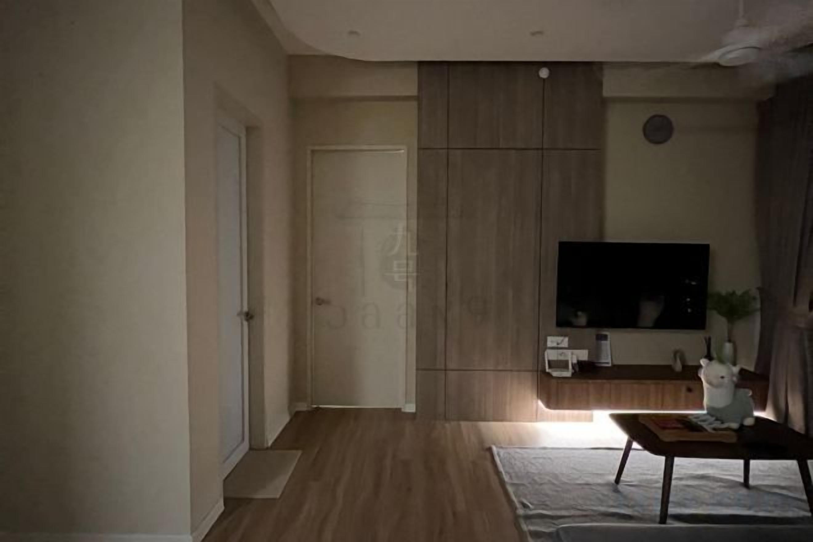 A living room with a flat-screen TV, a wooden cabinet, and a small table with a plant.