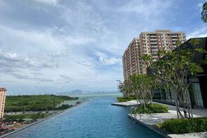 A long swimming pool with a view of a cityscape and a body of water in the distance. - Urban Suites Jelutong 3BR Apartment with Infinity Pool · Near George Town · 18min to Airport (George Town)