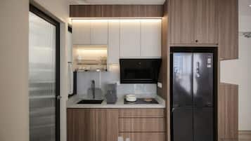 A modern kitchen with wooden cabinets, a black refrigerator, and a microwave.