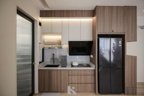 Una cocina moderna con armarios de madera, un refrigerador negro y un microondas.