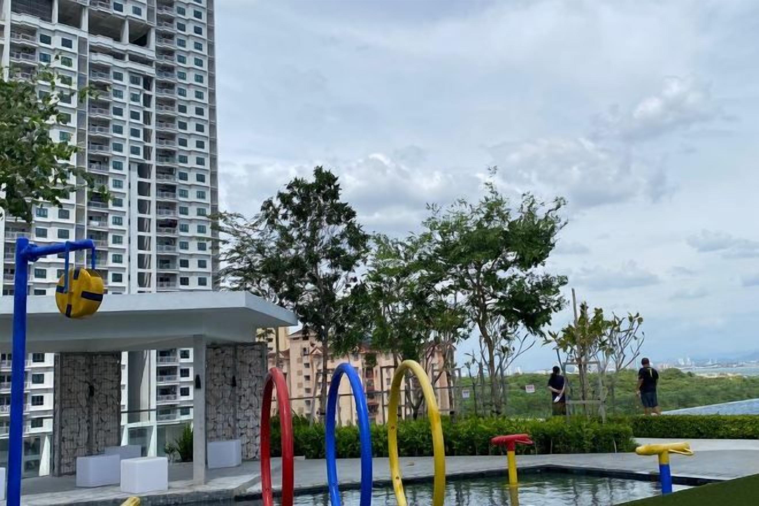 A residential area with a swimming pool, a tall building, and a few people in the distance.