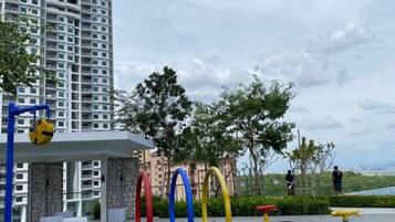 A residential area with a swimming pool, a tall building, and a few people in the distance.