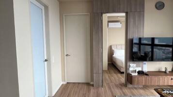 A hotel room with a bed, a TV, a desk, and a view of the city.