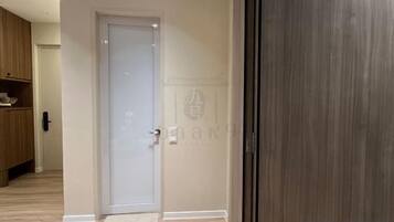 A room with a closed door, a wooden floor, and a visible doormat.