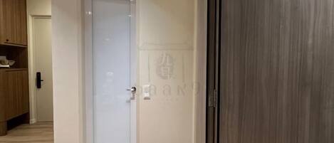 A room with a closed door, a wooden floor, and a visible doormat.