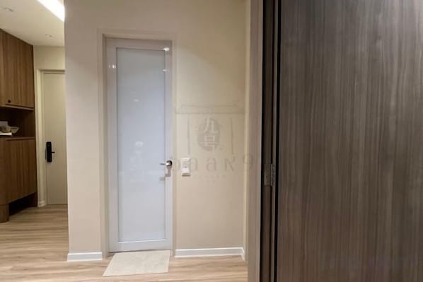 A room with a closed door, a wooden floor, and a visible doormat. - Urban Suites Jelutong 3BR Apartment with Infinity Pool · Near George Town · 18min to Airport (George Town)