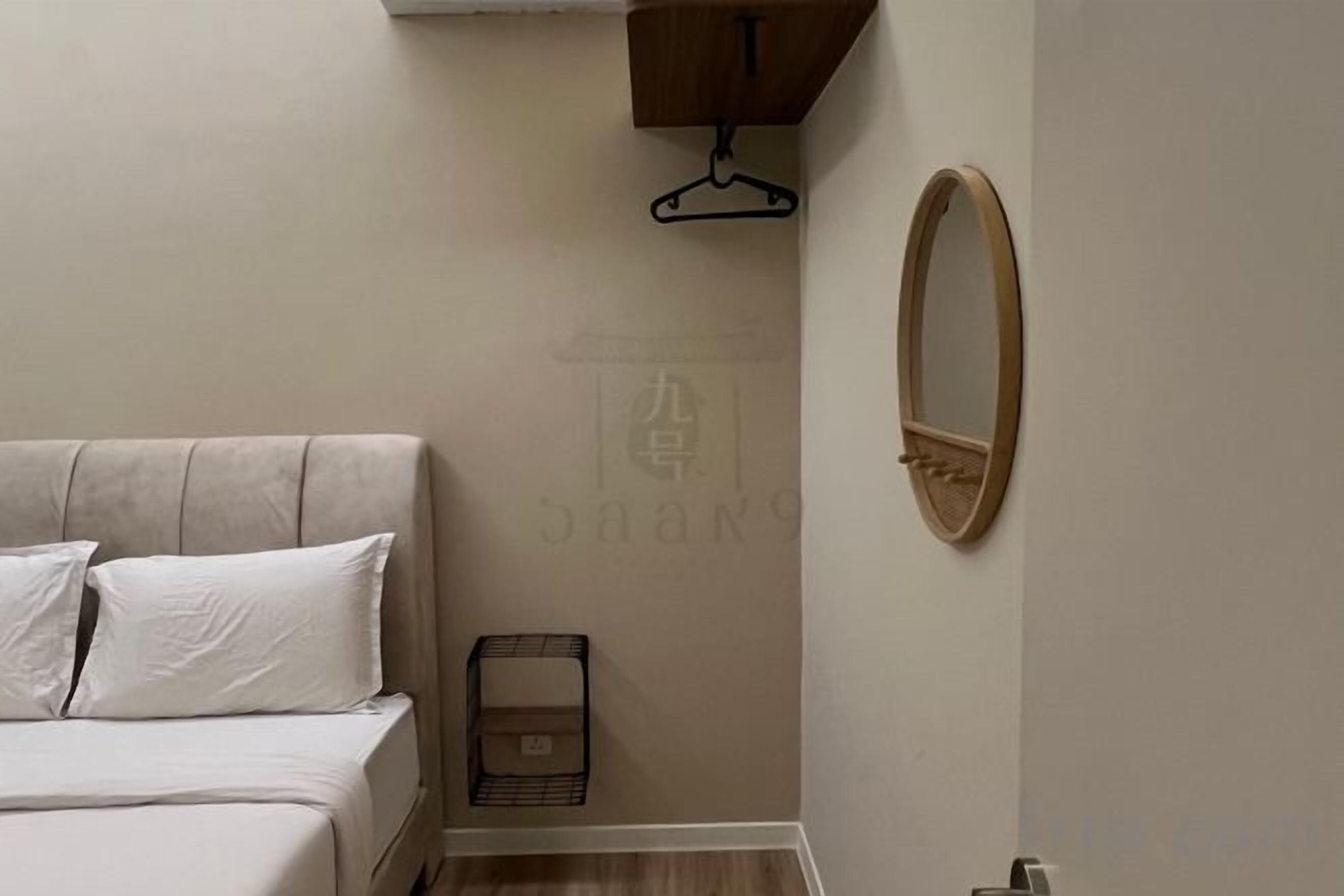 Un dormitorio con cama, lámpara colgante y espejo en la pared.