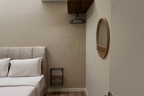 A bedroom with a bed, a hanging light fixture, and a mirror on the wall. - Urban Suites Jelutong 3BR Apartment with Infinity Pool · Near George Town · 18min to Airport (George Town)