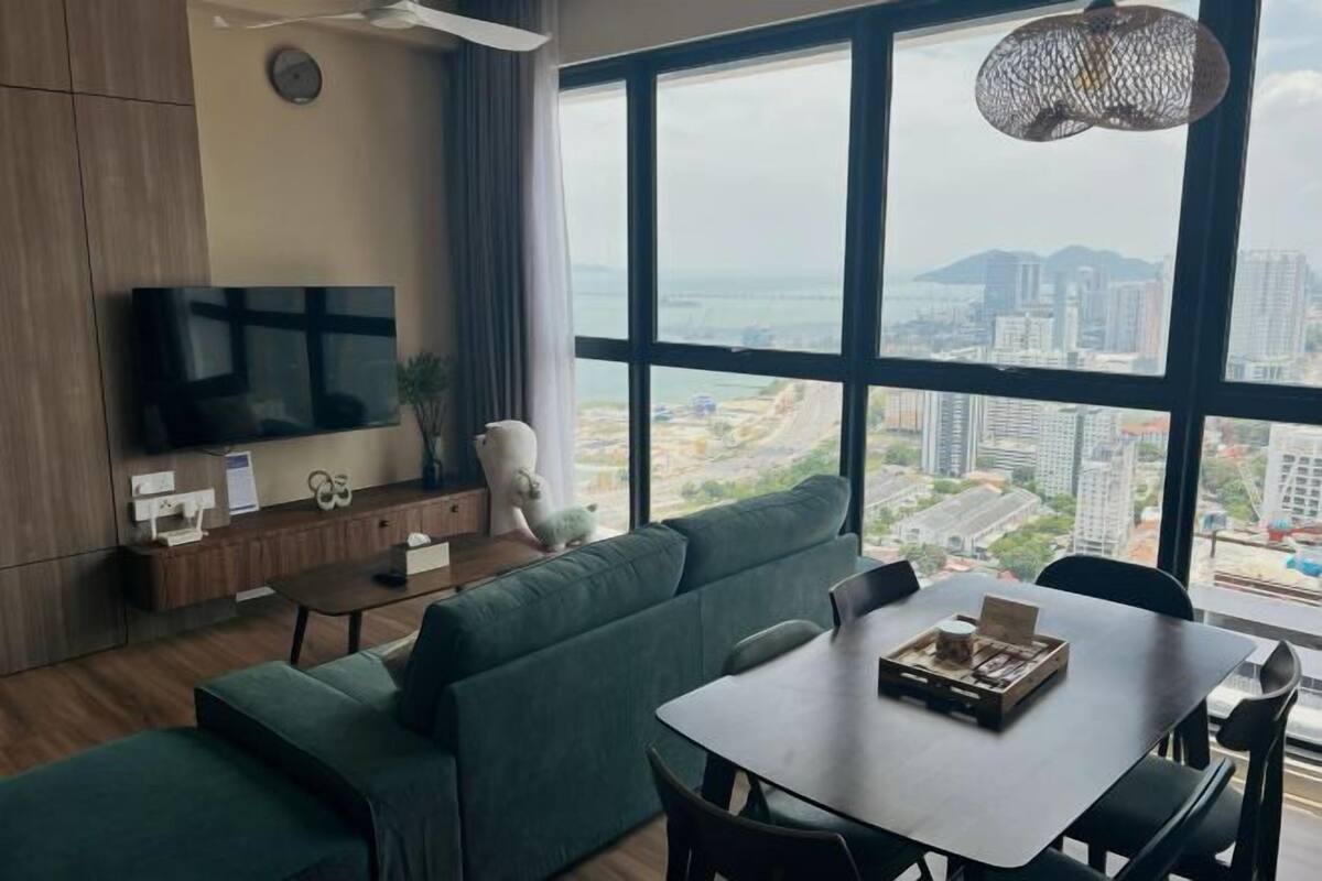 A modern living room with a large TV, a dining table, and a sofa.