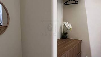 A hallway with a wooden cabinet, a hanging black hanger, and a potted orchid.