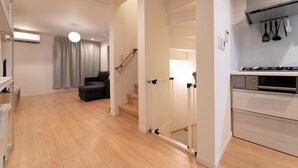 A modern kitchen with a gas stove, white cabinets, and a staircase leading to another level. - Satellite Hotel Roppongi 2nd (Tokyo)