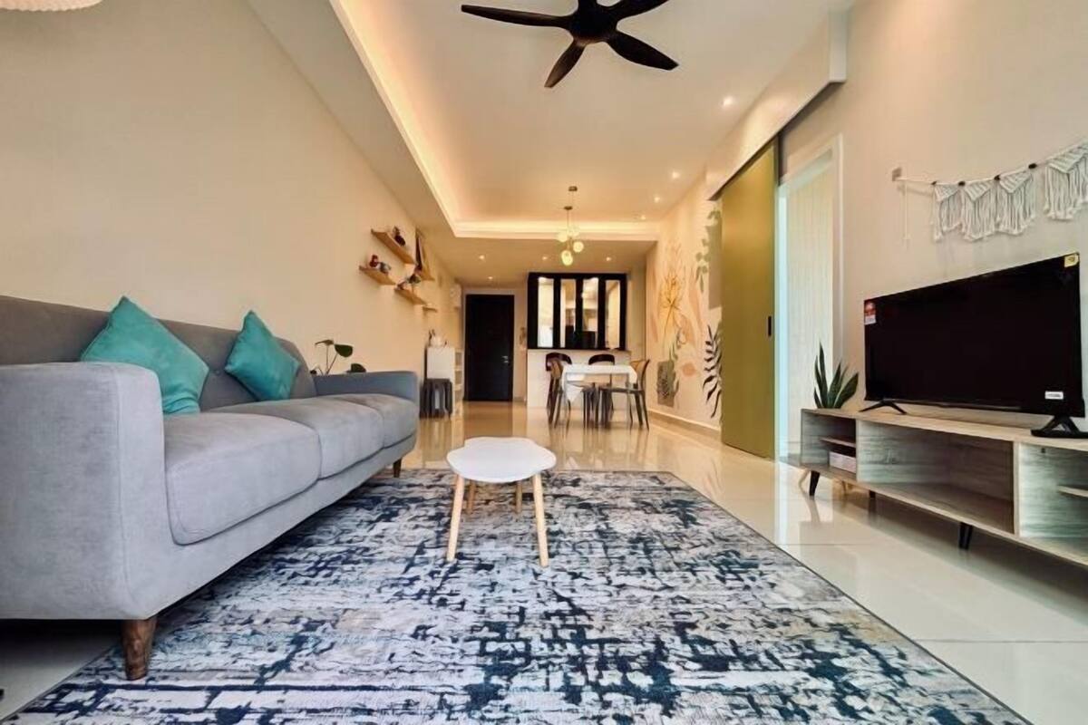 A modern living room with a sofa, a coffee table, a TV, and a dining area in the background.