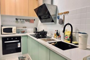 A compact kitchen with a microwave, stove, sink, and various kitchen utensils.