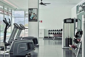 A gym with treadmills, a wall-mounted weight machine, and a rack of dumbbells.
